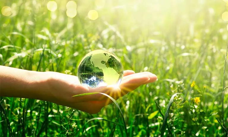 Earth crystal glass globe in human hand on grass background